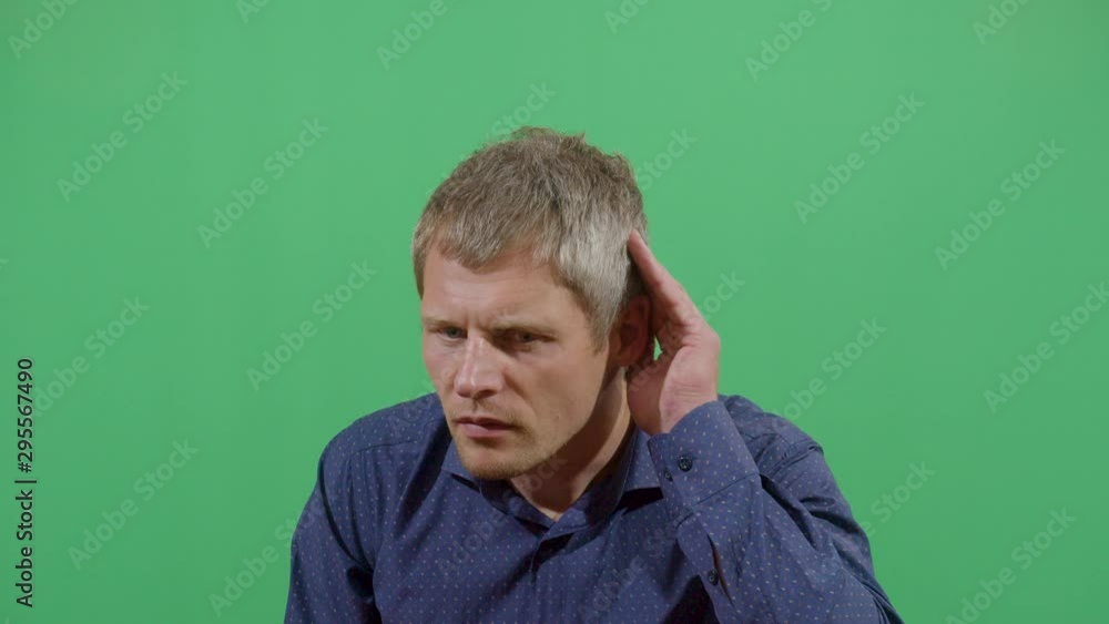Adult Man Using Hands As Hearing Device And Facial Expression Of Listening Better. Studio Isolated Shot Against Green Screen Background Adult Man Using Hands As Hearing Device And Facial Expression Of Listening Better. Studio Isolated Shot Against Green Screen Background