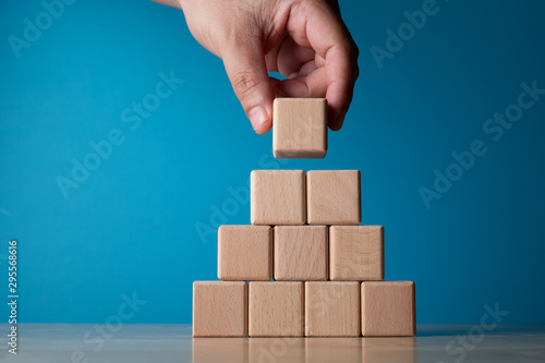 Hand arranging block on blue background. Business concept on progress or building something. photo