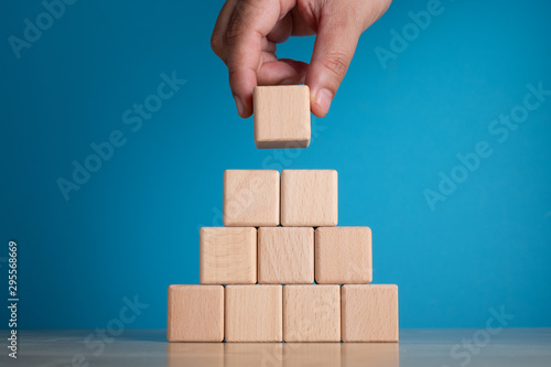 Hand arranging block on blue background. Business concept on progress or building something. photo