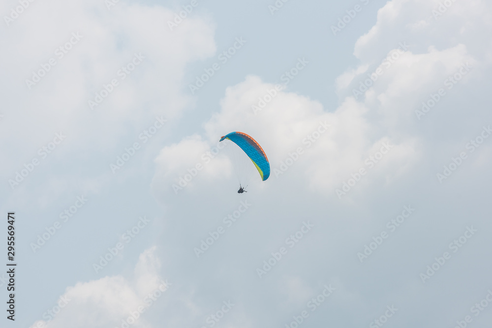 A blue paraglider flying in the background of the far sky white clouds A blue paraglider flying in the background of the far sky white clouds