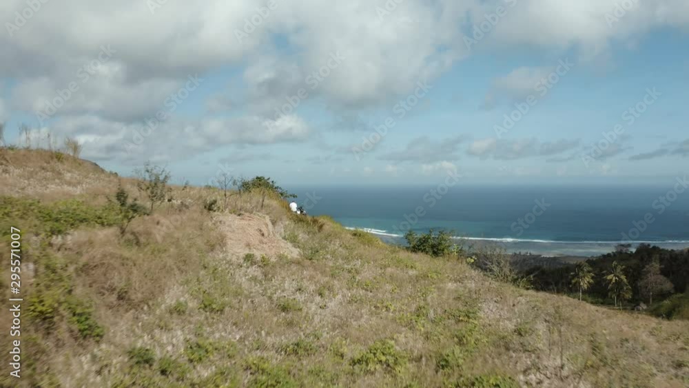 Forward drone shot above green mountains, near the coastline, with the ocean in the background, in Lombok, Indonesia Forward drone shot above green mountains, near the coastline, with the ocean in the background, in Lombok, Indonesia