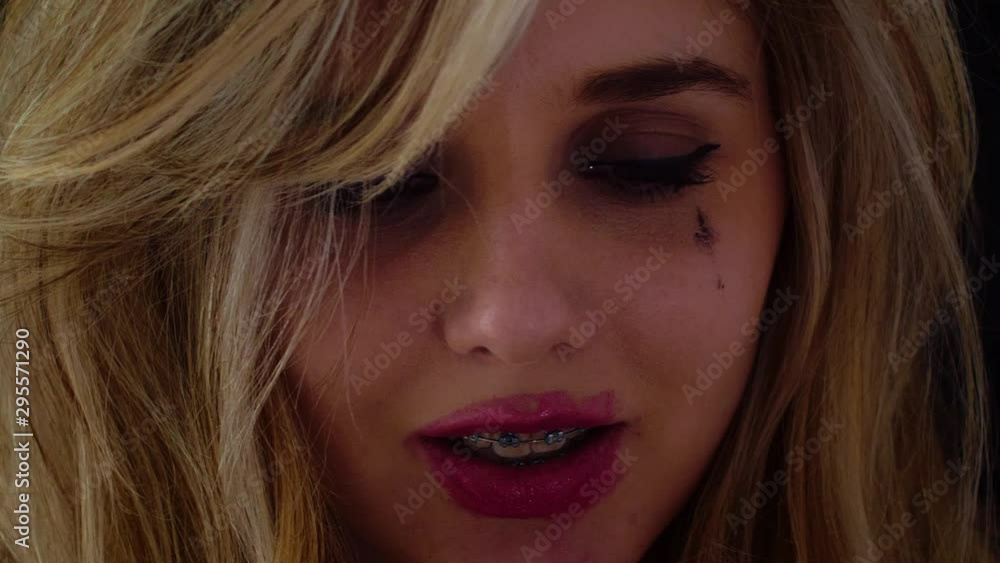 Woman looking crazy puts on messy pink lipstick; mascara running; low key light. Woman looking crazy puts on messy pink lipstick; mascara running; low key light.