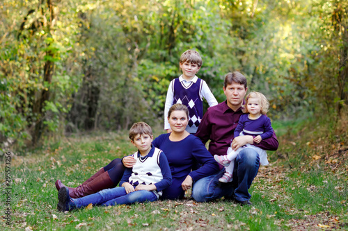 Portrait of young parents with three children. Mother, father, two kids brothers boys and little cute toddler sister girl having fun together in autumn forest. Happy family of five © Irina Schmidt