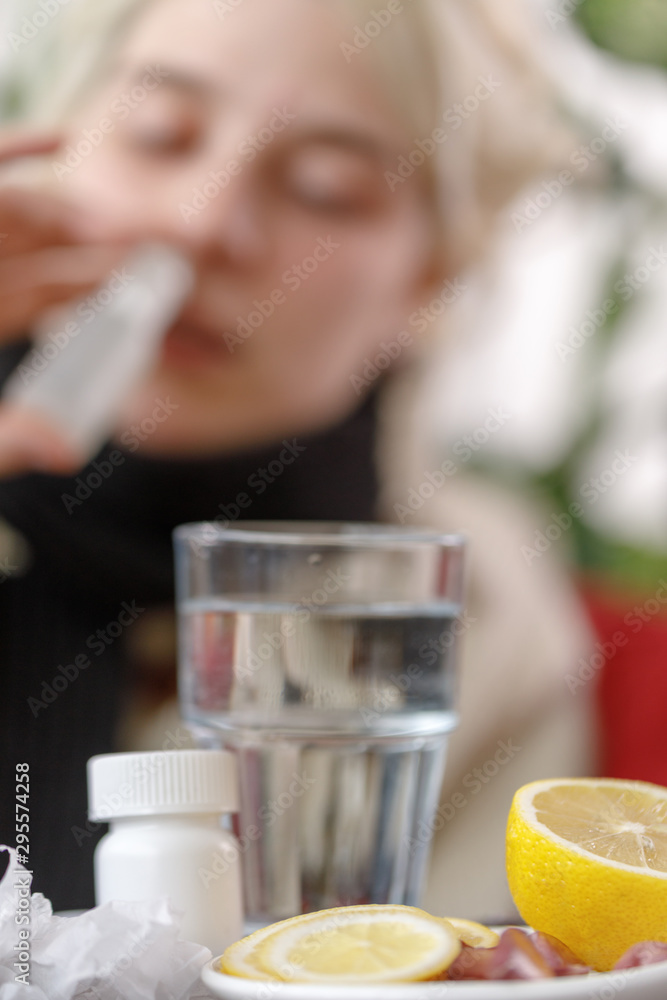 The girl in the sweater is sick lying on the couch. Colds and flu. The patient caught a cold, feeling sick and uses drops for the nose. Unhealthy girl. The girl in the sweater is sick lying on the couch. Colds and flu. The patient caught a cold, feeling sick and uses drops for the nose. Unhealthy girl.