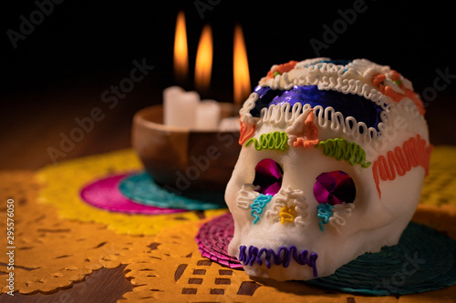 Sugar skull with burning candles and colored papers photo