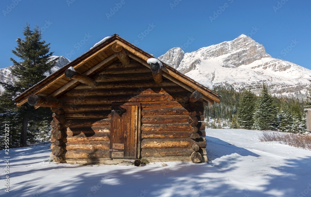 Vintage landmark log cabin and Distant Snowcapped Mountain Peaks on great hiking trail to Skoki area of Banff National Park, Canadian Rockies Alberta Canada