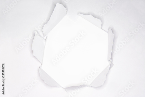 Ripped hole in the paper with torn edges on the white background