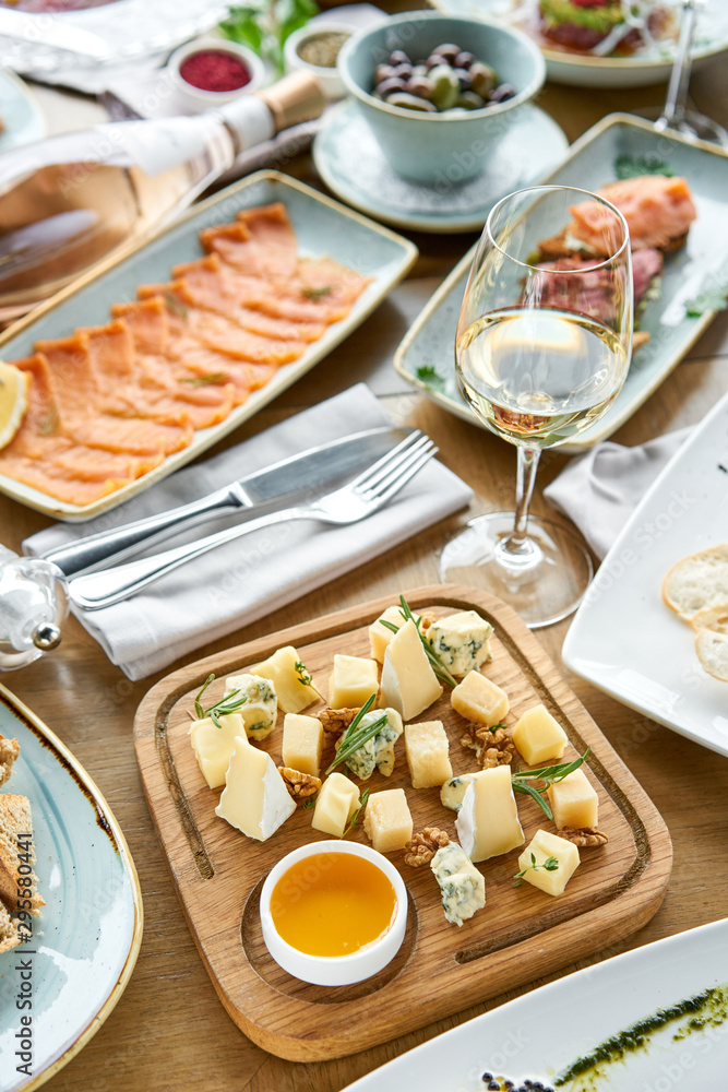 Cheese plate. Focus on delicious cheese mix with walnuts, honey on wooden table. Various snacks and antipasti on the table. Restaurant menu. Cheese plate. Focus on delicious cheese mix with walnuts, honey on wooden table. Various snacks and antipasti on the table. Restaurant menu.
