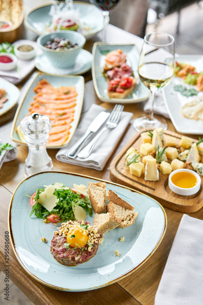 Beef tartar in the restaurant. Variety of dishes on the table. Various snacks and antipasti on the table. Restaurant menu. Italian cuisine Beef tartar in the restaurant. Variety of dishes on the table. Various snacks and antipasti on the table. Restaurant menu. Italian cuisine