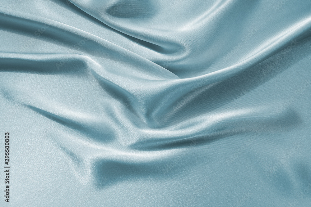 Delicate satin draped fabric of blue color texture for festive backgrounds Delicate satin draped fabric of blue color texture for festive backgrounds