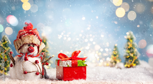 Beautiful winter background with  snowman and gift box on a wooden old desk, ...