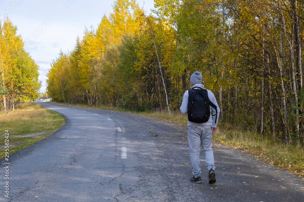 Tourist or traveler with a backpack in the autumn forest. Hiking. back view