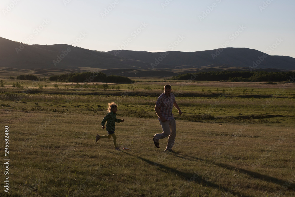 Fototapeta premium dad plays catch-up with daughter at sunset