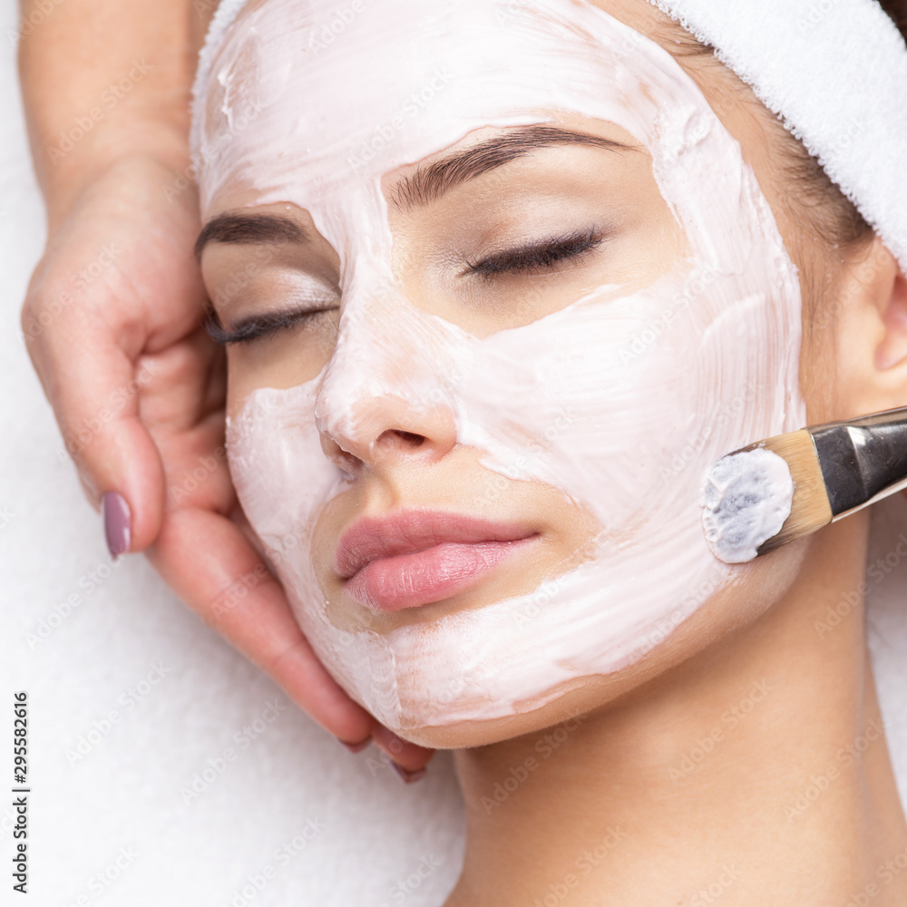 Woman receiving facial mask at beauty salon