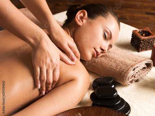 Beautiful woman relaxing with back massage at spa salon.
