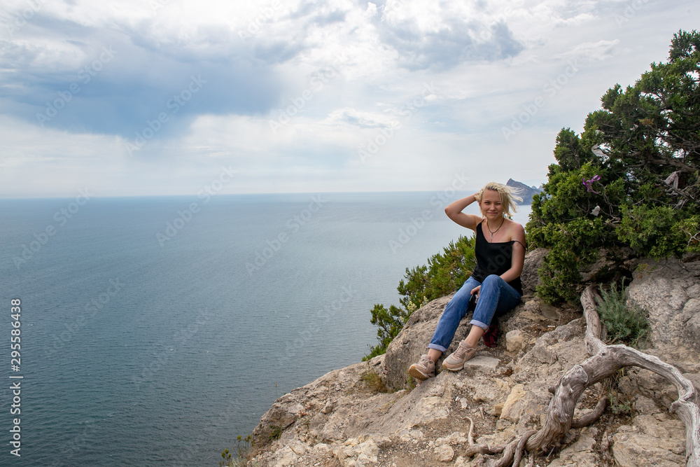 Girl traveler looks from the mountain to the sea Girl traveler looks from the mountain to the sea
