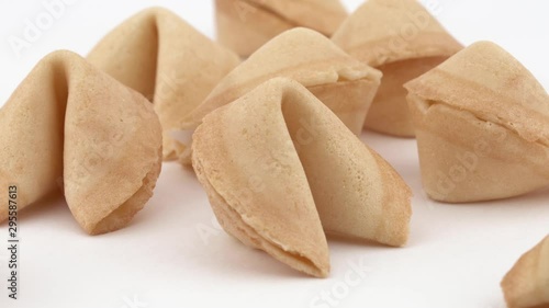 Close-up of a traditional Chinese fortune cookies spinning slowly on white table. Pastry and fortune telling concept. Isolated, on white background.