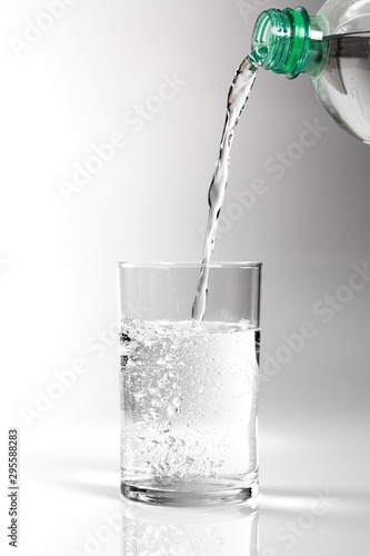 Pouring clear water into glass. Isolated on white background.