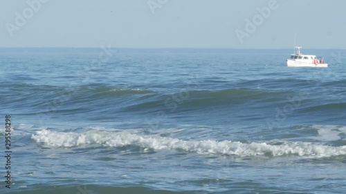 Fishing boat in ocean by beach as birds fly by 4k - OBX Outer Banks HAtteras