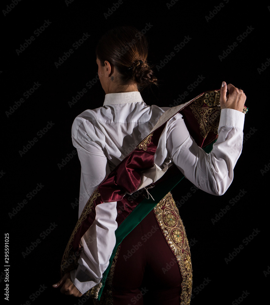 Woman bullfighter by dressing with vest on your back on a black background