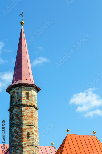 The tower with the spire and the red roofs of the Maltese style Adobe mansion on the sunlit background of the blue sky. photo