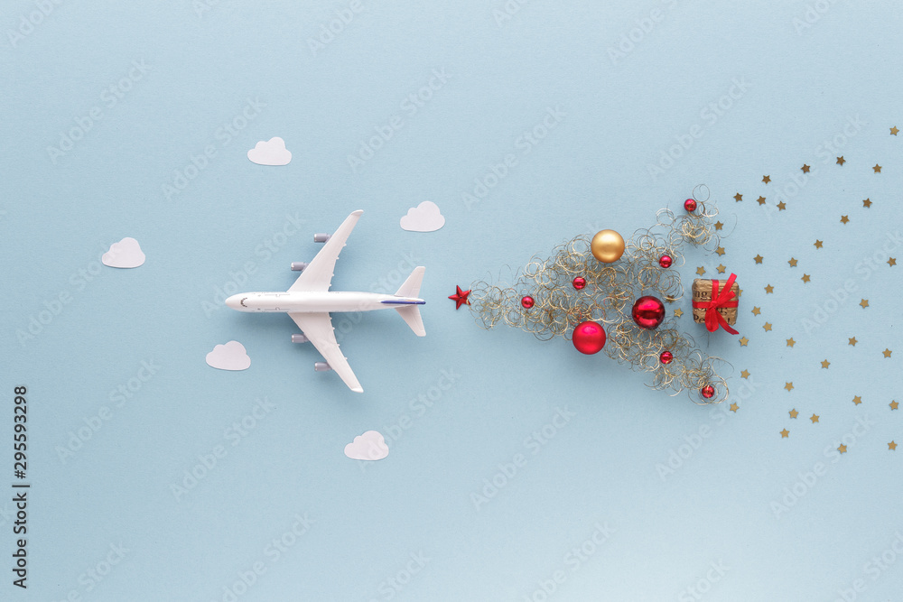 Fototapeta Christmas composition. Airplane flying in sky star gift bauble top view background with copy space for your text. Flat lay