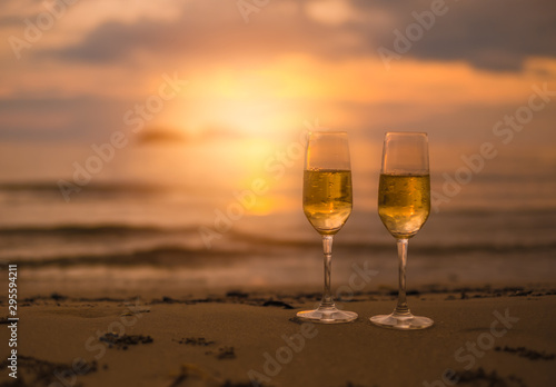 Two glasses of champagne on sandy beach  in beautiful sunset