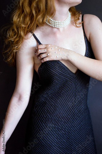 photo female figure in a black dress with a hand in pearls on a gray background