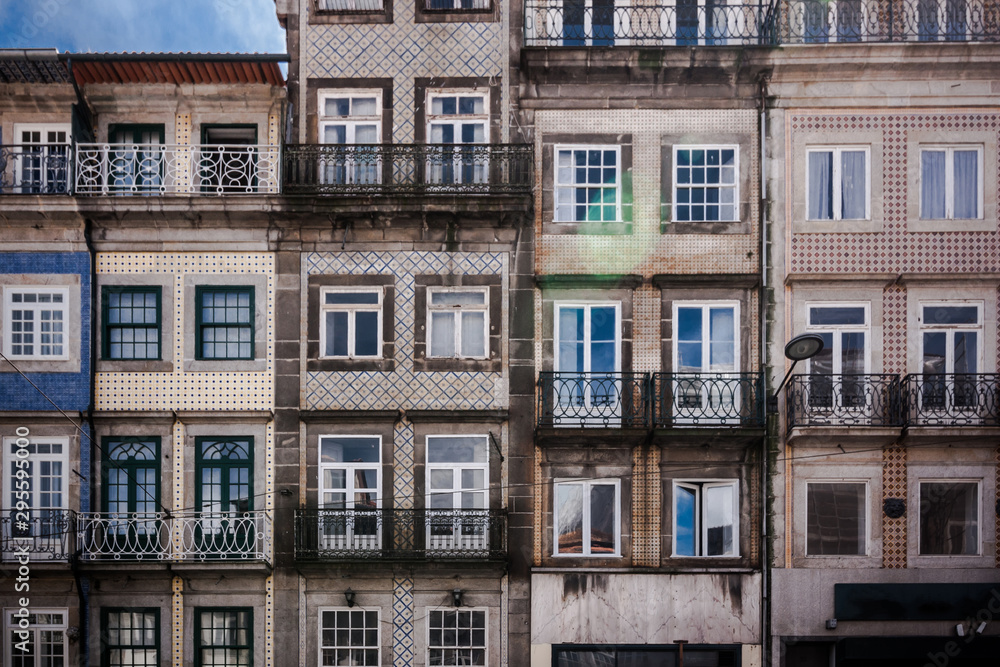 Historic old city buildings with portuguese tiles on the facade in Porto. Front view of typical portugal houses with balconies