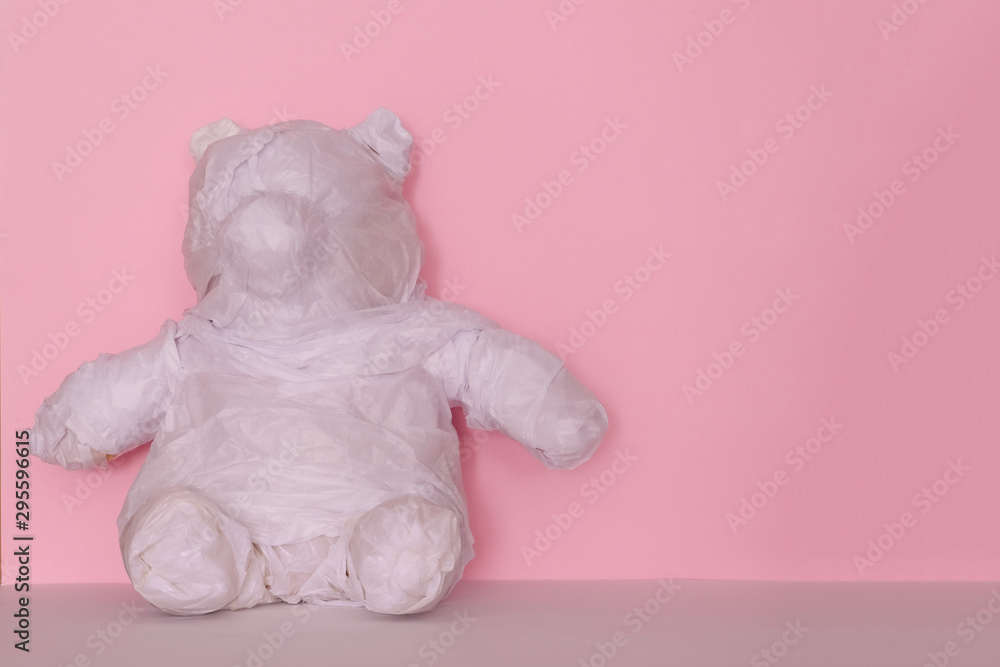 teddy bear wrapped in white paper for a gift on pink background teddy bear wrapped in white paper for a gift on pink background