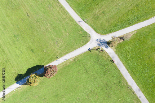 Bild auf Leinwand top drone aerial view to crossing road in green meadow with fall trees