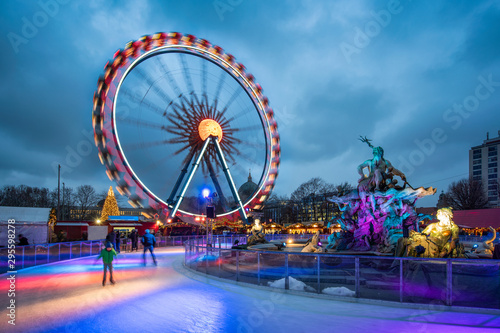Christmas market near the Neptune Fountain in Berlin with Ferris wheel and ice rink in winter