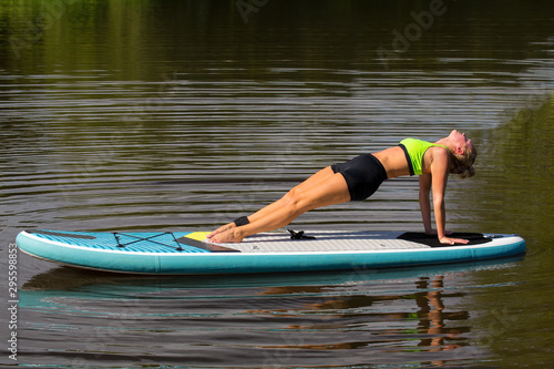 Woman planking backwards on SUP at water