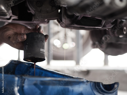 Close up Oil Filter. Professional car mechanic changing motor oil under car at the garage. Mechanic oil change service.      