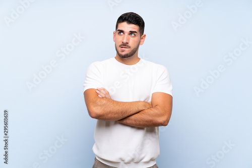 Caucasian handsome man over isolated blue background with confuse face expression