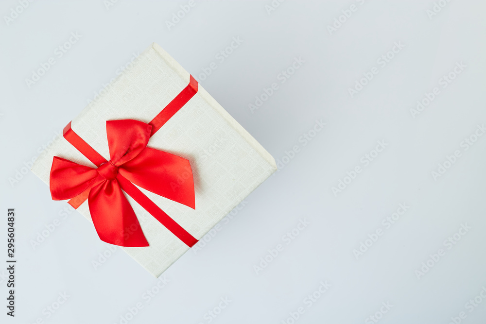 White gift box with red ribbon bow on white White gift box with red ribbon bow on white