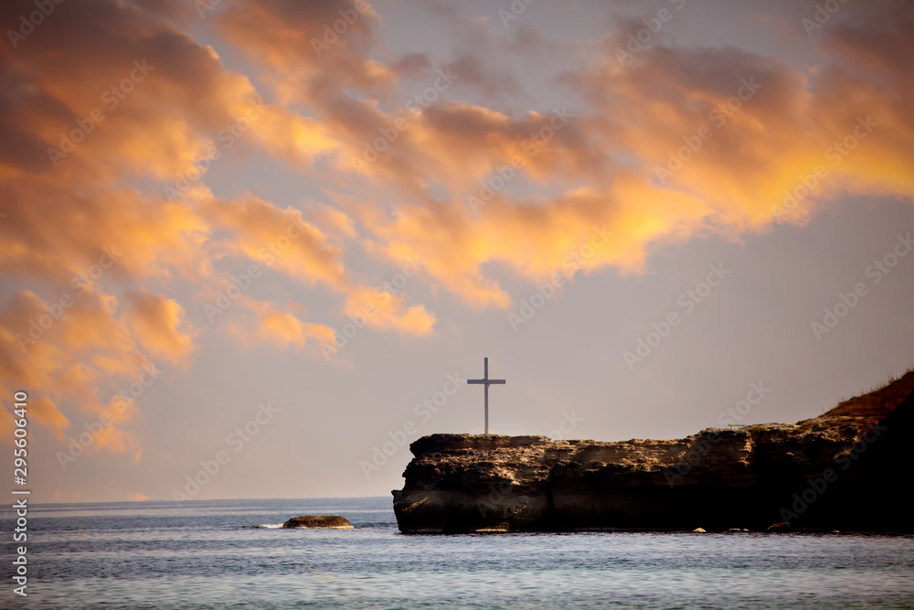 A memorial cross on the cliff looking out to sea during sunset dramatic sunset