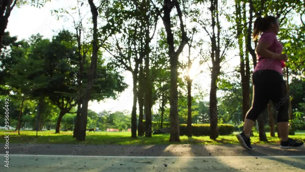 Slow Motion Side view of women asian running, jogging in the park and evening sun. Good health and exercise Slow Motion Side view of women asian running, jogging in the park and evening sun. Good health and exercise
