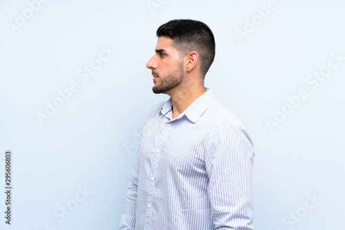 Caucasian handsome man over isolated blue background looking side