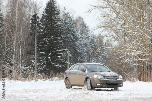 The car is gray on the road in the forest. A trip to the countryside on a winter weekend. The car on the road in front of the winter park.