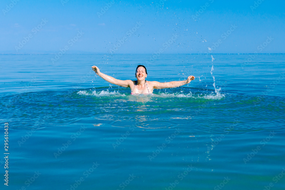 Excited female jumping with widespread hands in shallow sea water