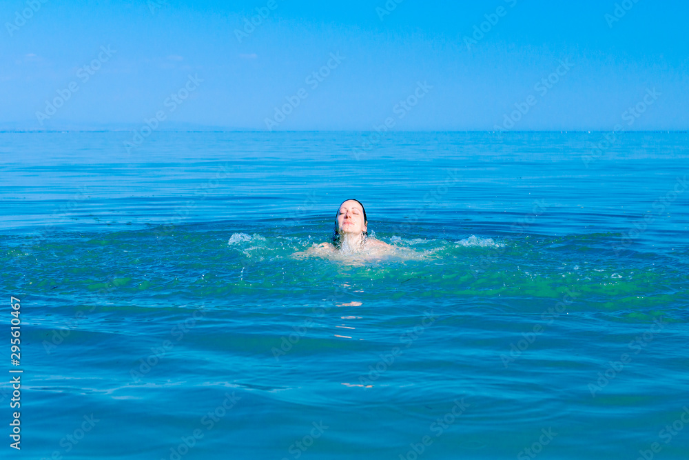 Excited female jumping with widespread hands in shallow sea water