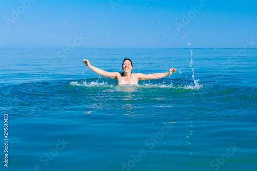 Excited female jumping with widespread hands in shallow sea water