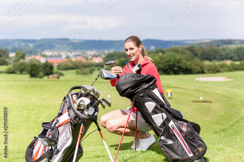 Female golfer holding club from bag