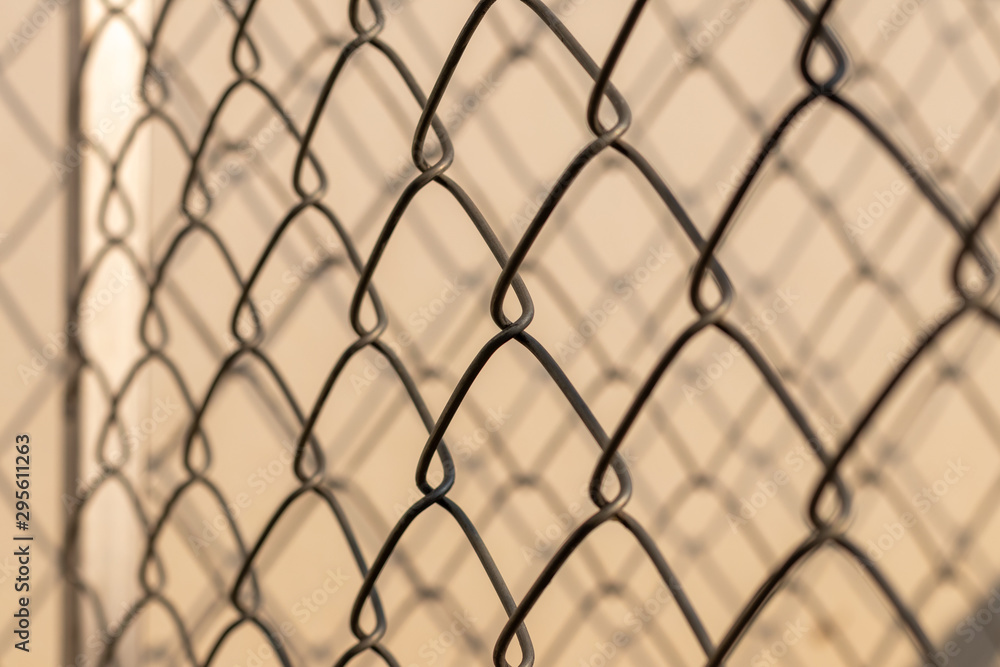 Fototapeta premium Light, shadow, woven metal grating fence.