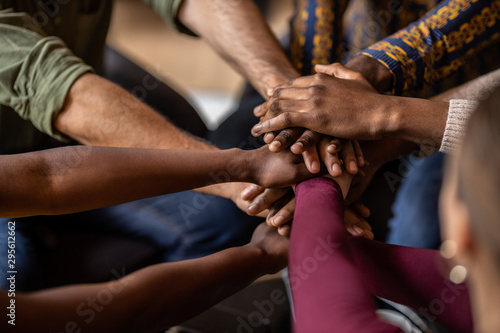 Cropped close of diverse business people putting their hands on top of each other wearing casual clothes and african patterns.