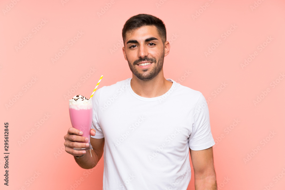 Young man with strawberry milkshake over isolated pink background Young man with strawberry milkshake over isolated pink background