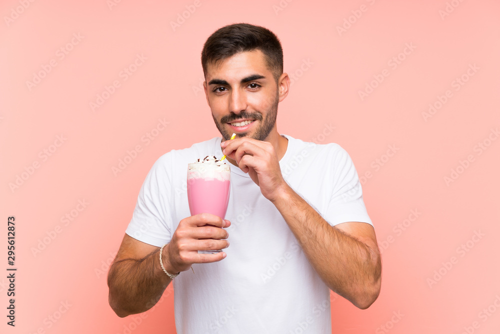Young man with strawberry milkshake over isolated pink background Young man with strawberry milkshake over isolated pink background