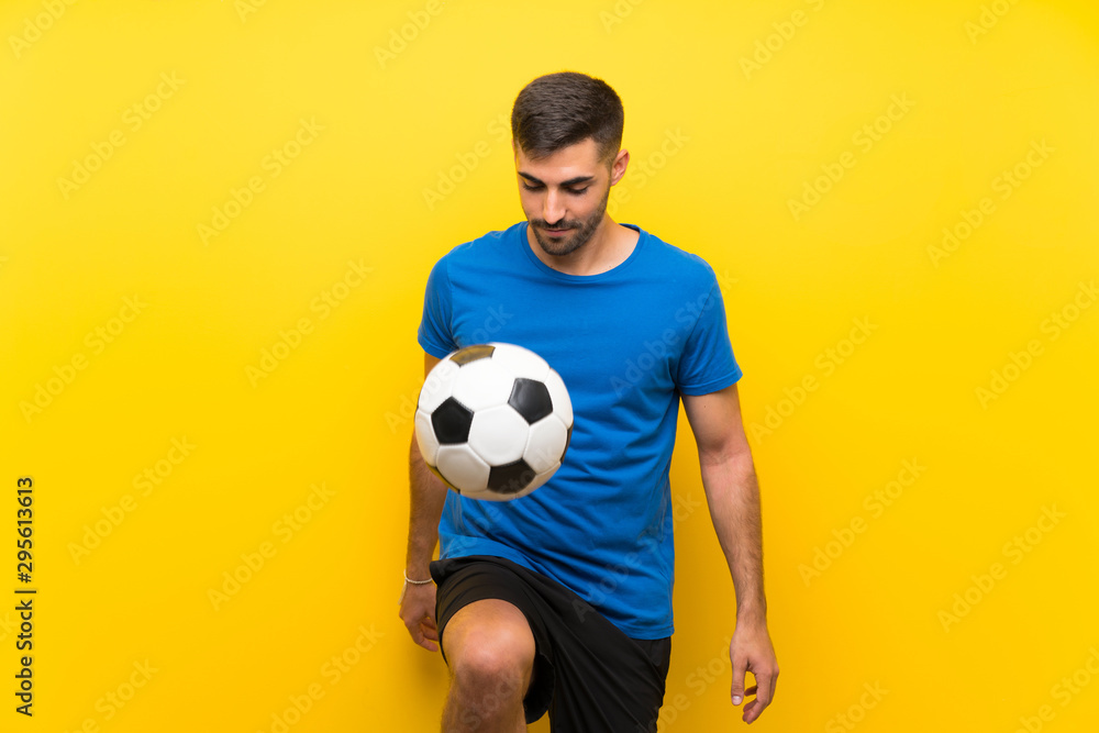 Young handsome football player man over isolated yellow wall Young handsome football player man over isolated yellow wall