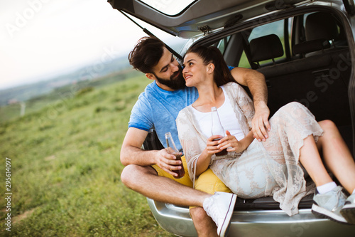 Loving couple sitting in the car trank during trip in the nature photo